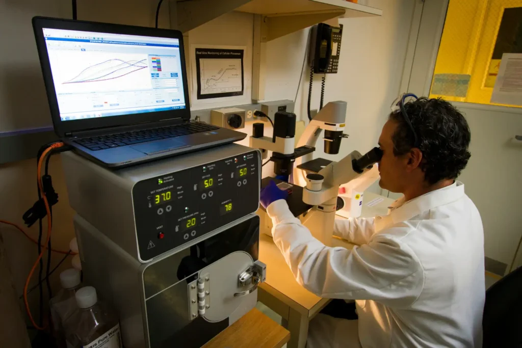 Cientista utilizando equipamentos de laboratório para testes, pesagens e processos técnicos na indústria, com monitor, microscópio e instrumentos especializados.