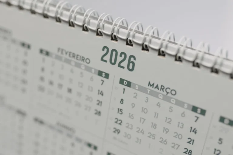 Calendário anual 2026 em close, com páginas em espiral e marcações de meses como fevereiro e março, simbolizando planejamento e estratégia editorial.